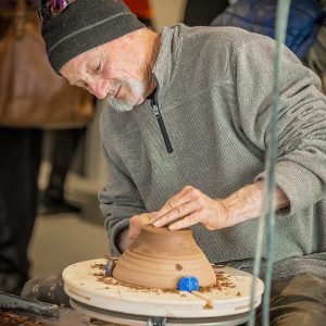 an artist shapes a ceramic piece on a potting wheel