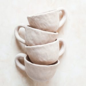 Three white coffee cups are stacked on a white background