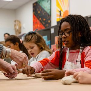 Kids working on art in Kids Class - hand of a teacher to help - Mark Arts in Wichita KS
